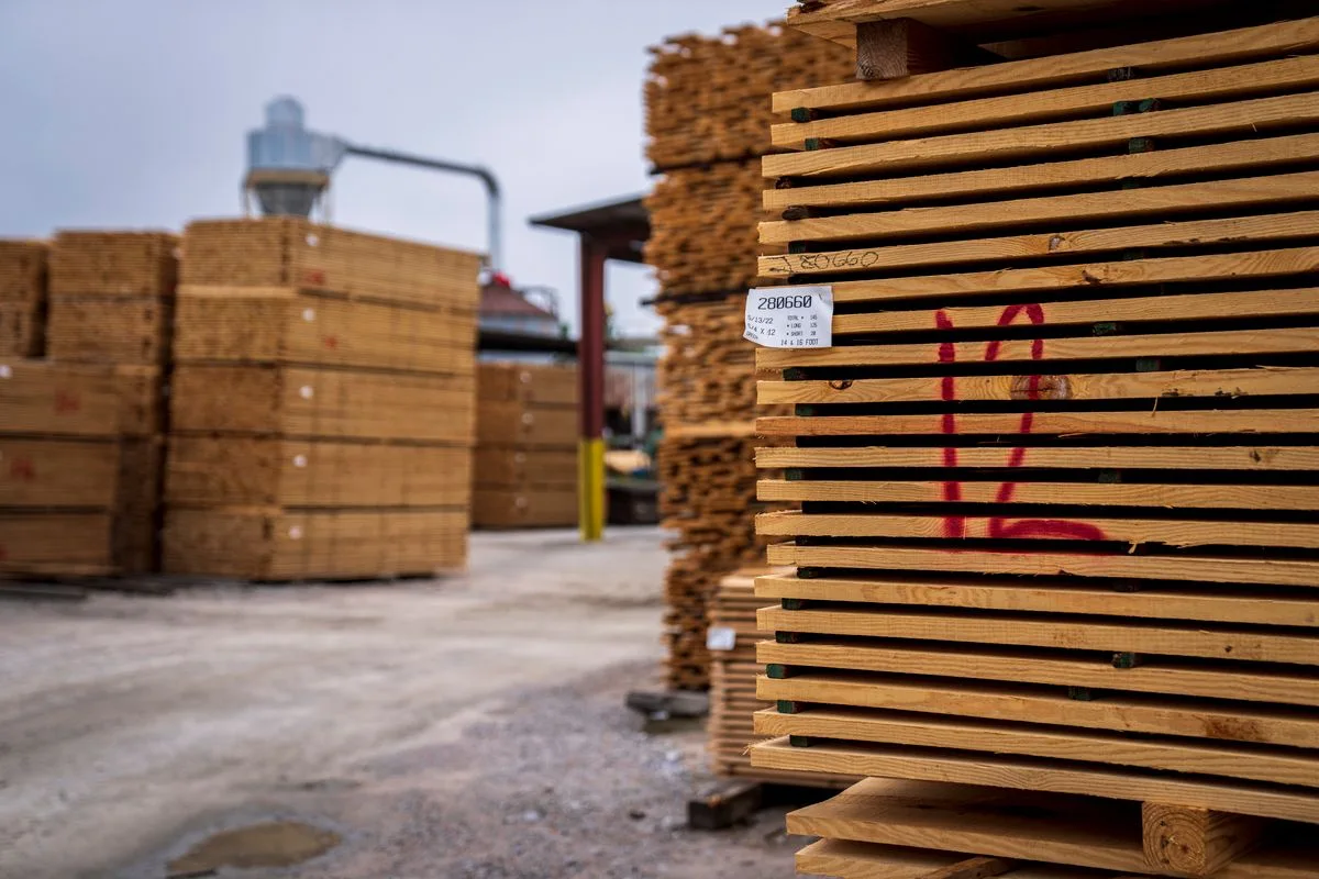 Timber stacked in a lumber yard; illustrative building-supply photograph